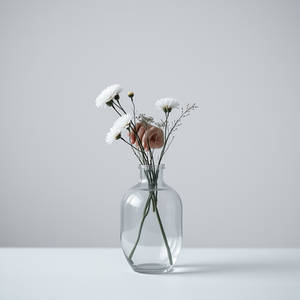 A clear glass vase with delicate white flowers on a pale table